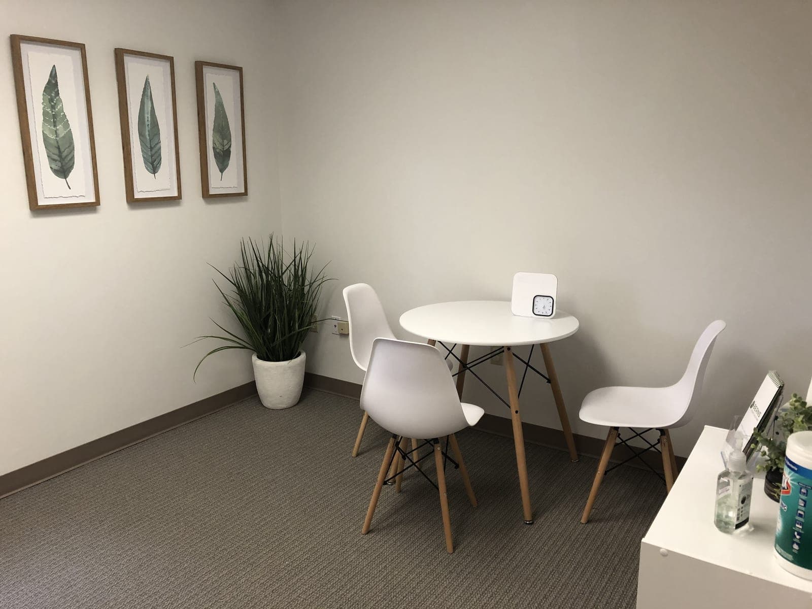 Therapy room at the Green Hills office with a white table and chairs and leaf prints on the wall